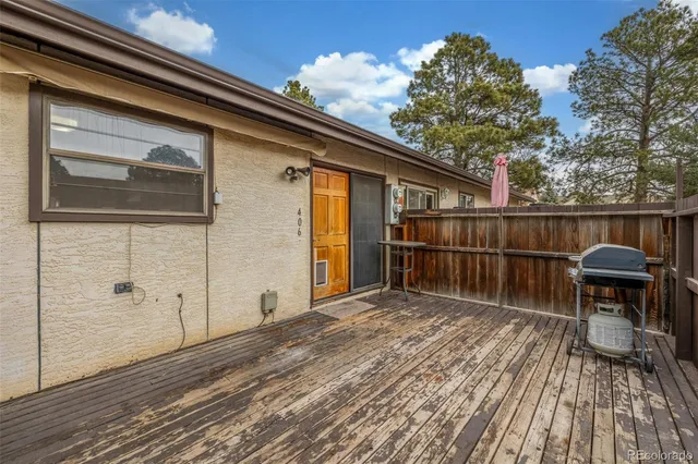a balcony with wooden floor and fence next to a yard