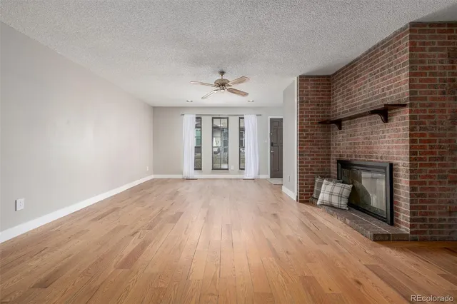 an empty room with wooden floor a fireplace and windows