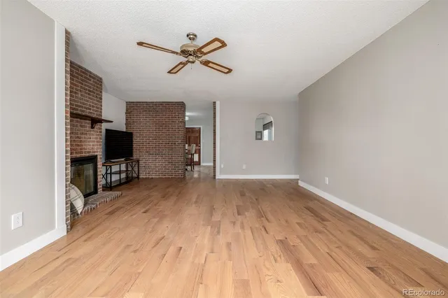 a view of empty room with wooden floor and ceiling fan