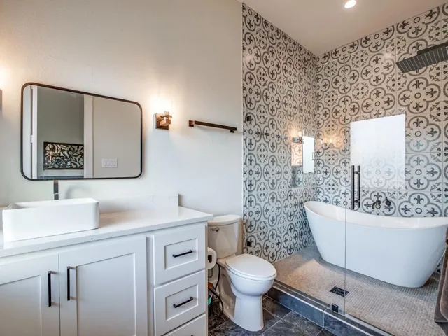 a spacious bathroom with a double vanity sink toilet mirror and bathtub