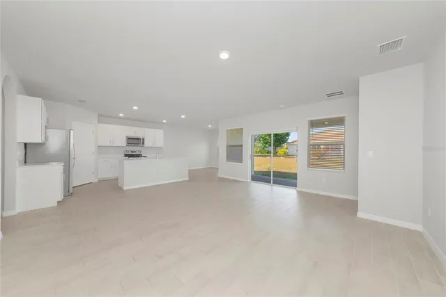 a view of empty room with kitchen and windows