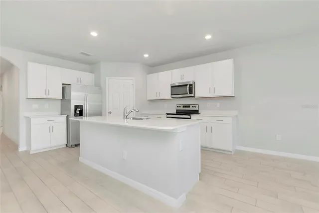 a kitchen with cabinets a sink a window and stainless steel appliances
