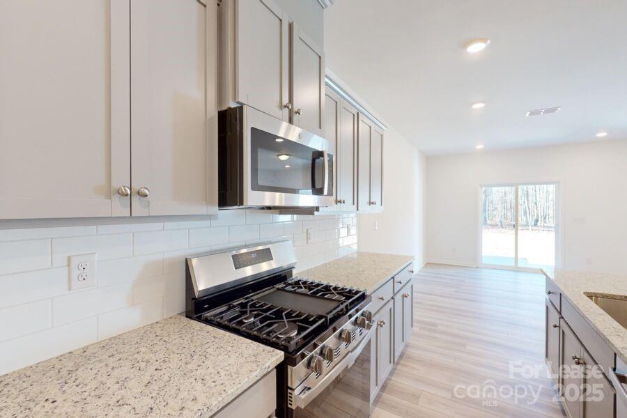 3519 Secrest Landing Monroe, NC 28110 - Photo 6 of 25 a kitchen with stainless steel appliances granite countertop a stove a sink and a microwave