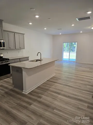 a kitchen with a sink cabinets wooden floor and a window