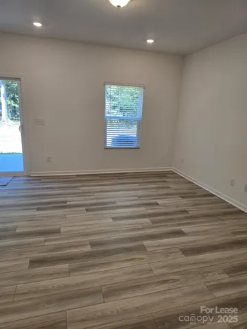 a view of an empty room with window and wooden floor