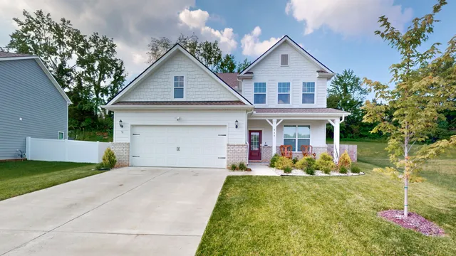 a front view of house with yard and trees in the background