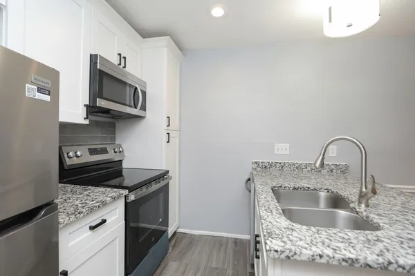 a view of a refrigerator in kitchen and an empty room