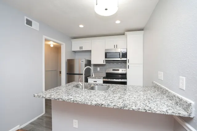a kitchen with granite countertop a sink and a stove top oven