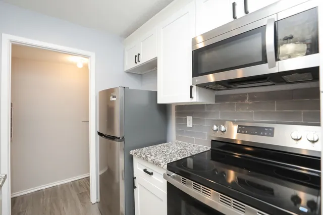 a view of a refrigerator in kitchen and an empty room