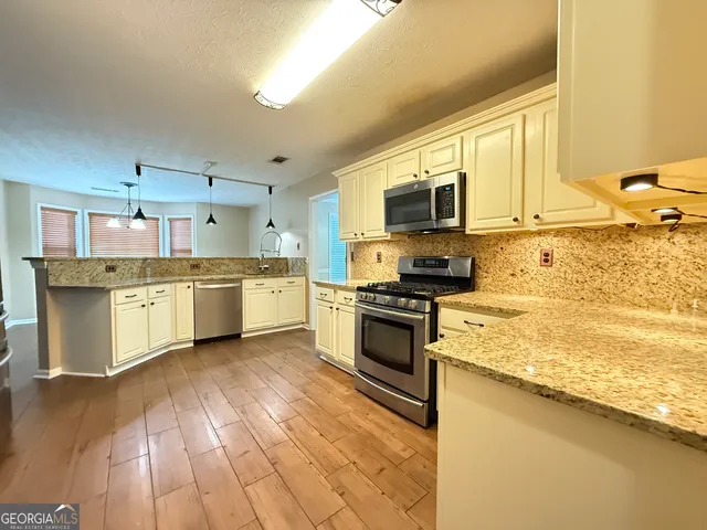a kitchen with stainless steel appliances granite countertop a stove a sink and a microwave