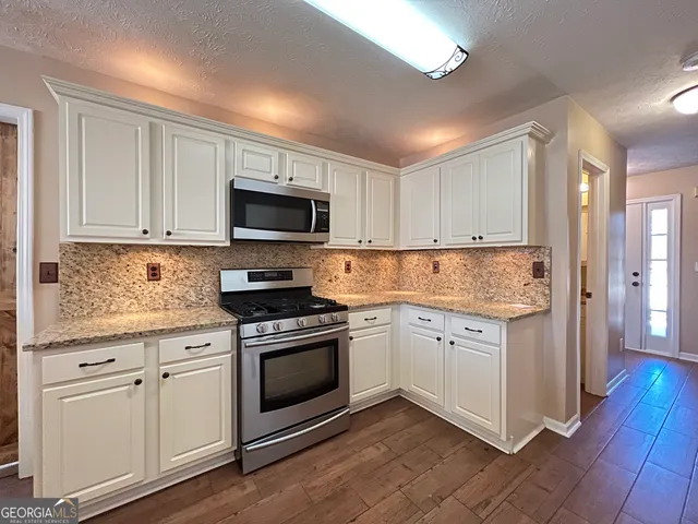a kitchen with granite countertop white cabinets white stainless steel appliances with a sink and dishwasher