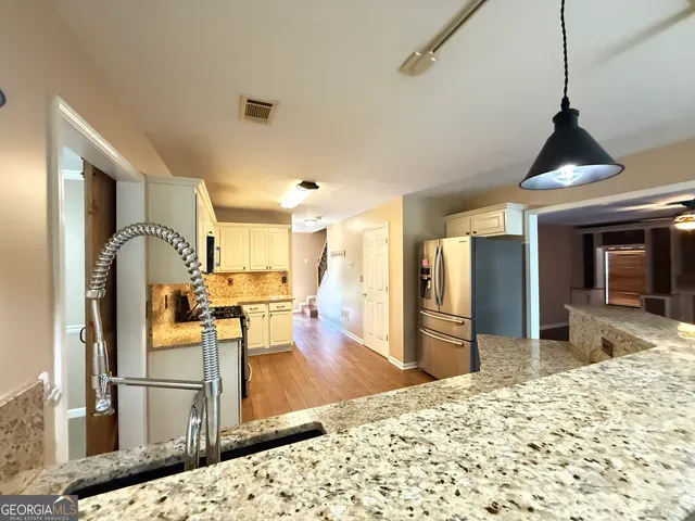 a kitchen with stainless steel appliances kitchen island granite countertop a refrigerator and cabinets