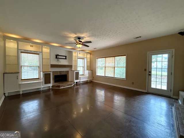 an empty room with wooden floor fireplace and windows