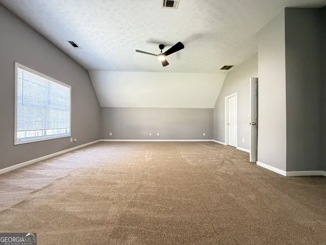 an empty room with windows and ceiling fan