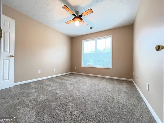 an empty room with windows and fan