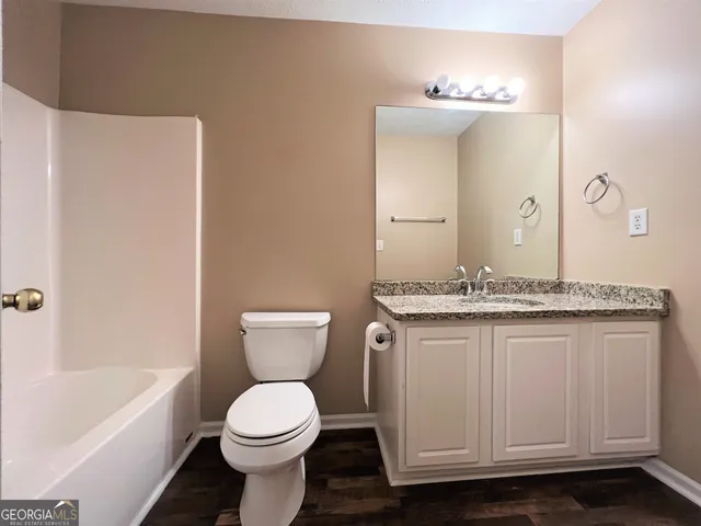 a bathroom with a granite countertop toilet sink and mirror