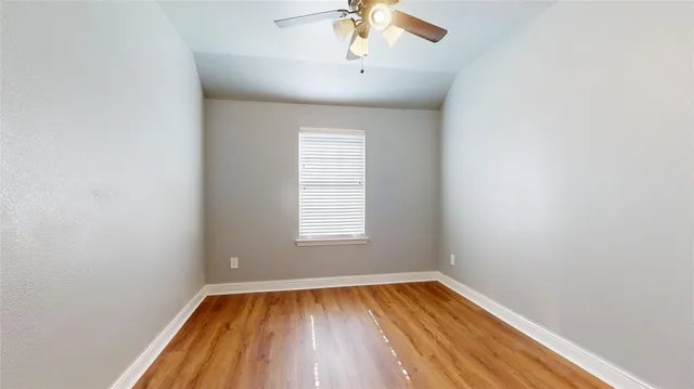 an empty room with a window and wooden floor