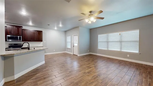 a view of an empty room with window and wooden floor