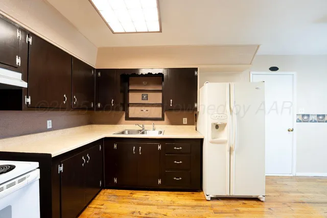 a kitchen with stainless steel appliances kitchen island granite countertop a refrigerator and a sink