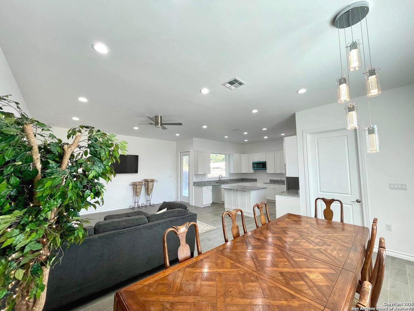 97 Berwick Road Victoria, TX 77904 - Photo 10 of 35 a large white kitchen with granite countertop a stove a sink a dining table and chairs with wooden floor