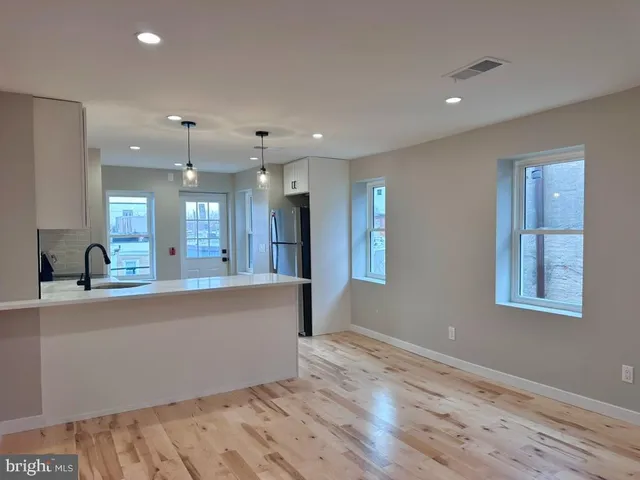 a large kitchen with stainless steel appliances a large counter top a sink and a wooden floor