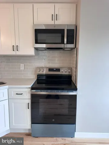 a kitchen with stainless steel appliances granite countertop white cabinets a microwave oven and a sink