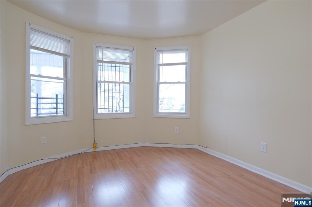 84 Scheerer Avenue Newark, NJ 07112 - Photo 2 of 9 an empty room with wooden floor and windows