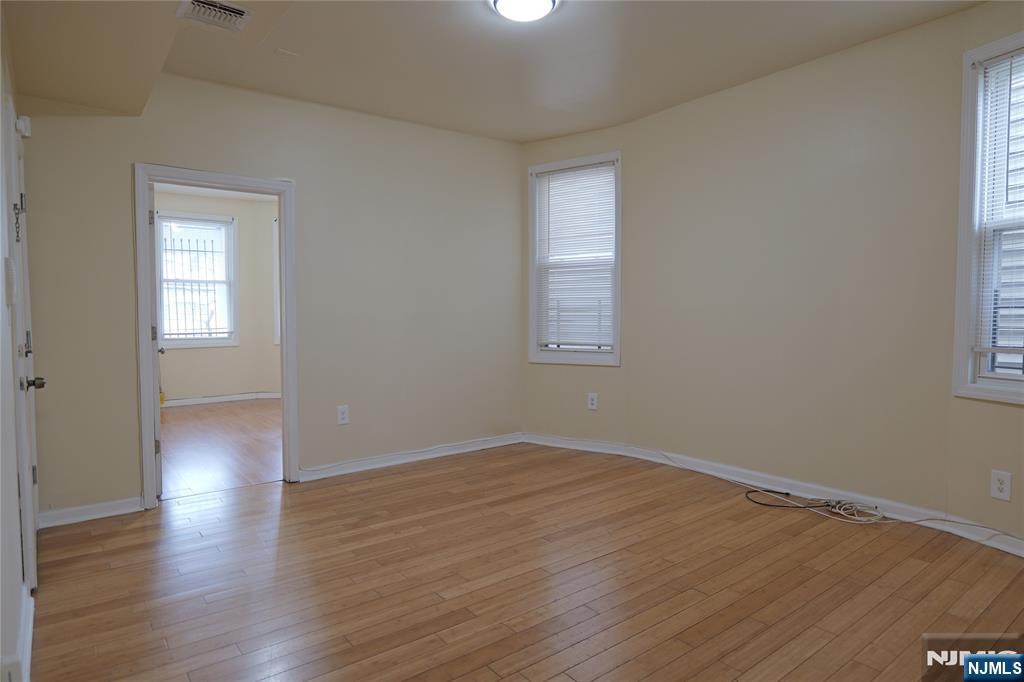 84 Scheerer Avenue Newark, NJ 07112 - Photo 3 of 9 an empty room with wooden floor and windows
