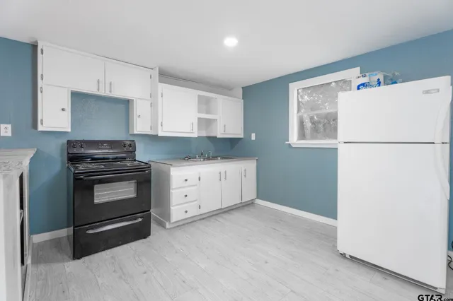 a kitchen with granite countertop a refrigerator stove and white cabinets