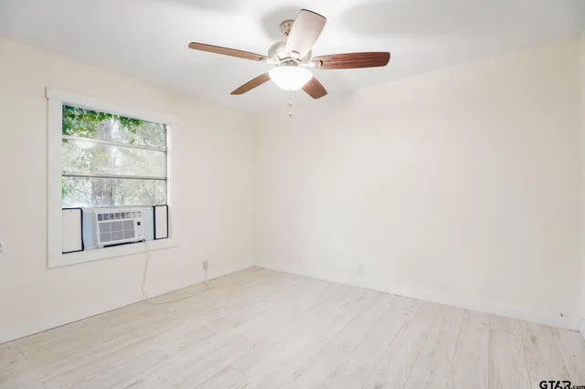an empty room with windows and fan