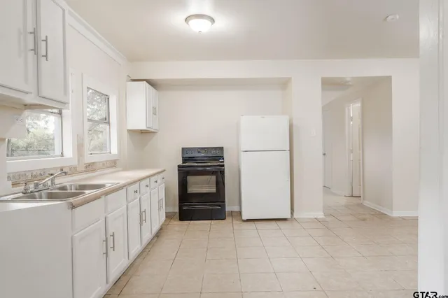 a kitchen with white cabinets and refrigerator