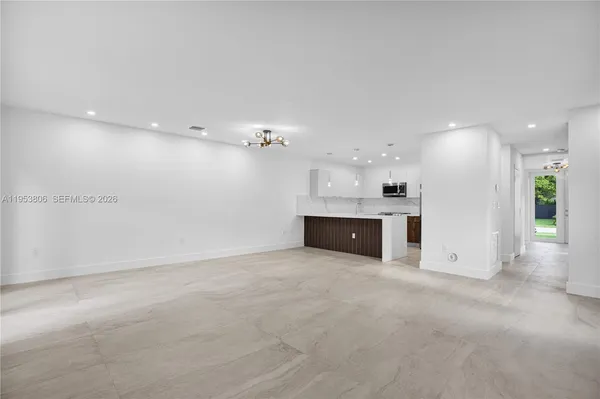 an empty room with kitchen view and a fireplace