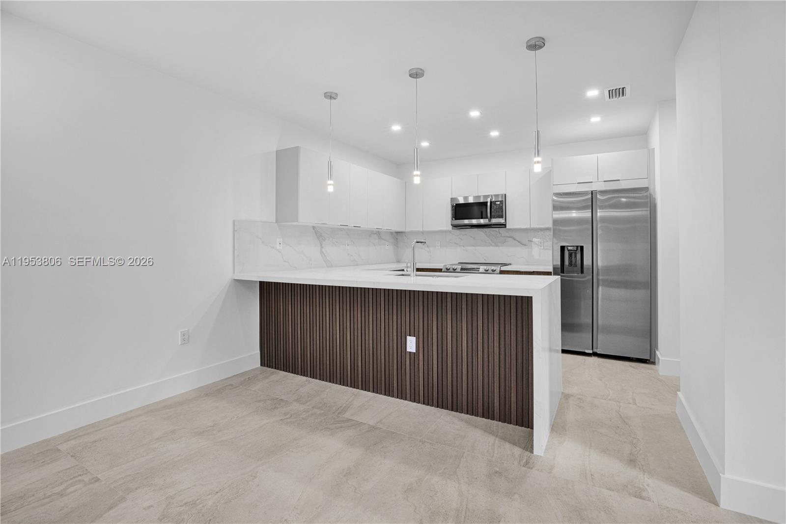 3433 Southwest 16th Terrace Miami, FL 33145 - Photo 7 of 26 a kitchen with kitchen island granite countertop wooden cabinets and stainless steel appliances