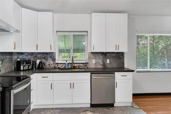 a kitchen with stainless steel appliances granite countertop a refrigerator sink and stove