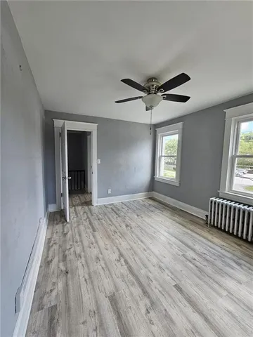 a view of an empty room with a window and wooden floor