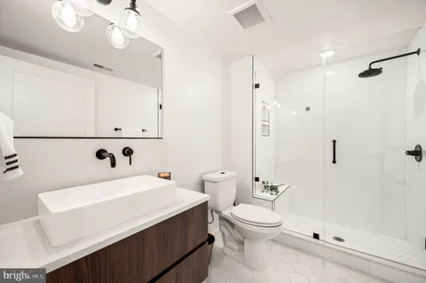 a bathroom with a toilet a sink a mirror and shower