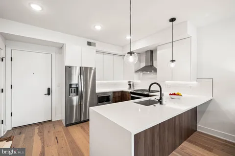 a kitchen that has a sink a refrigerator and a stove top oven with wooden floor