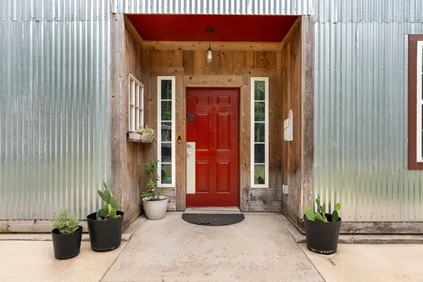 a front view of a house with a potted plant and floor to ceiling window