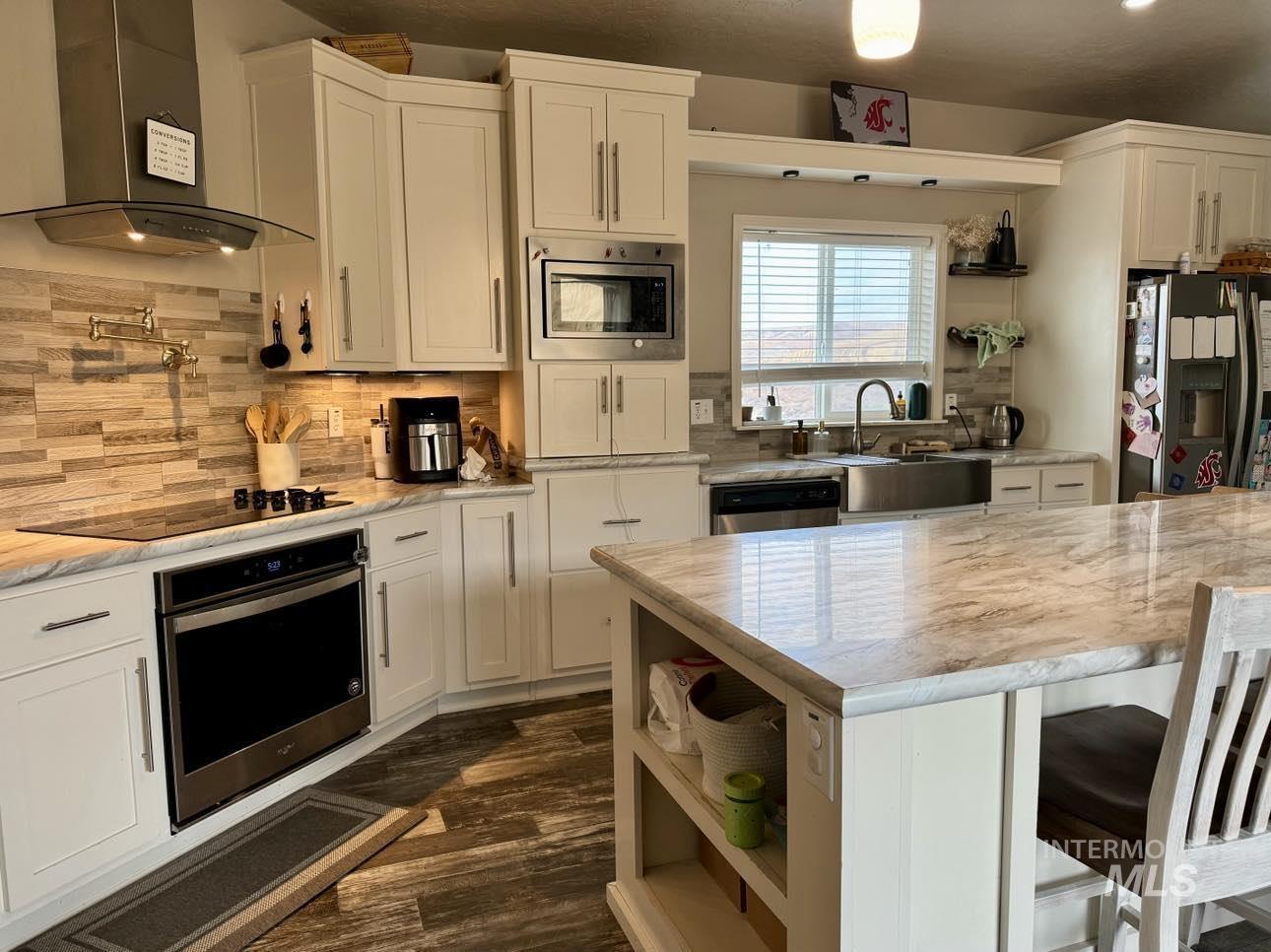 986 Parade Avenue Lapwai, ID 83540 - Photo 3 of 12 Kitchen featuring open shelves, wall chimney range hood, stainless steel appliances, and white cabinetry
