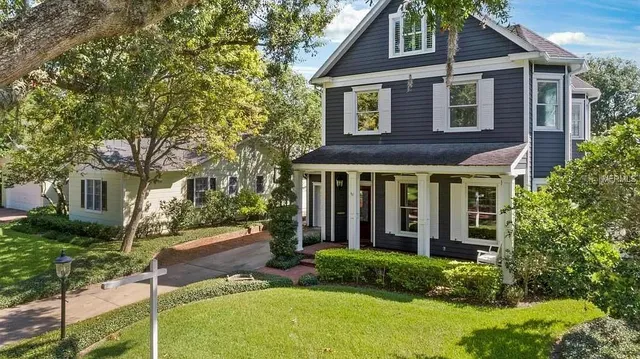 a view of a brick house with plants and large tree