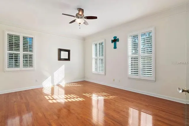 a view of an empty room with wooden floor and a window