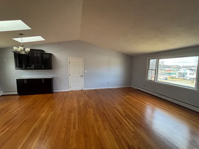 an empty room with windows fireplace and wooden floor
