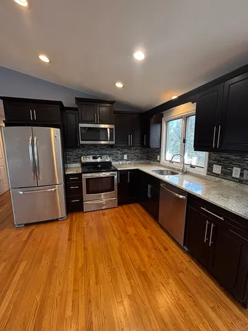 a large kitchen with stainless steel appliances granite countertop a stove a sink dishwasher and a refrigerator