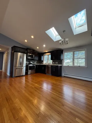a view of an empty room with wooden floor and windows