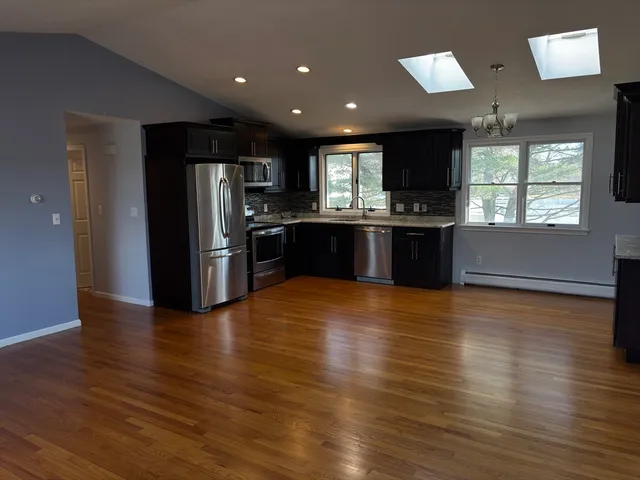 a view of kitchen with stainless steel appliances granite countertop a refrigerator and a stove top oven