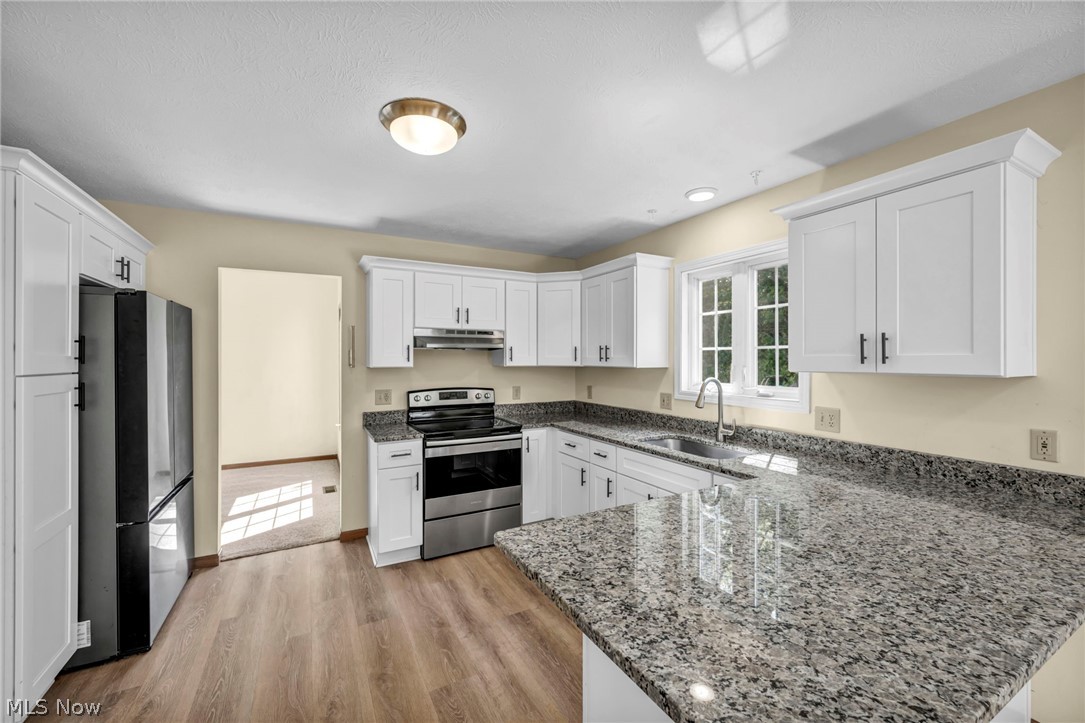9842 Johnnycake Ridge Road Mentor, OH 44060 - Photo 11 of 40 Well-appointed kitchen featuring white cabinetry, granite countertops, stainless steel appliances, wood-finish flooring, and a double window above the sink