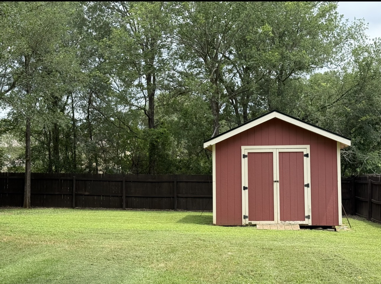 104 Spring Branch Bastrop, TX 78602 - Photo 9 of 32 A well-maintained storage shed stands ready for use in a verdant backyard, fully fenced for privacy.