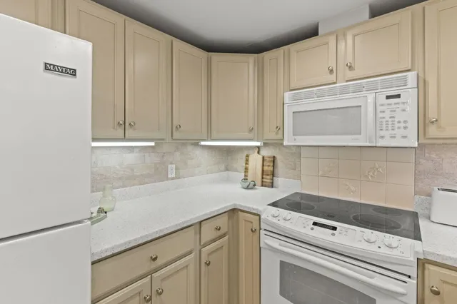 a kitchen with granite countertop white cabinets and white appliances