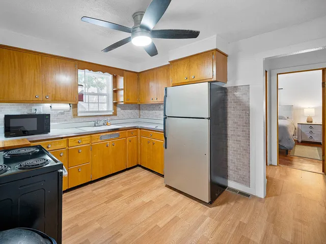 a kitchen with kitchen island wooden floors appliances and cabinets