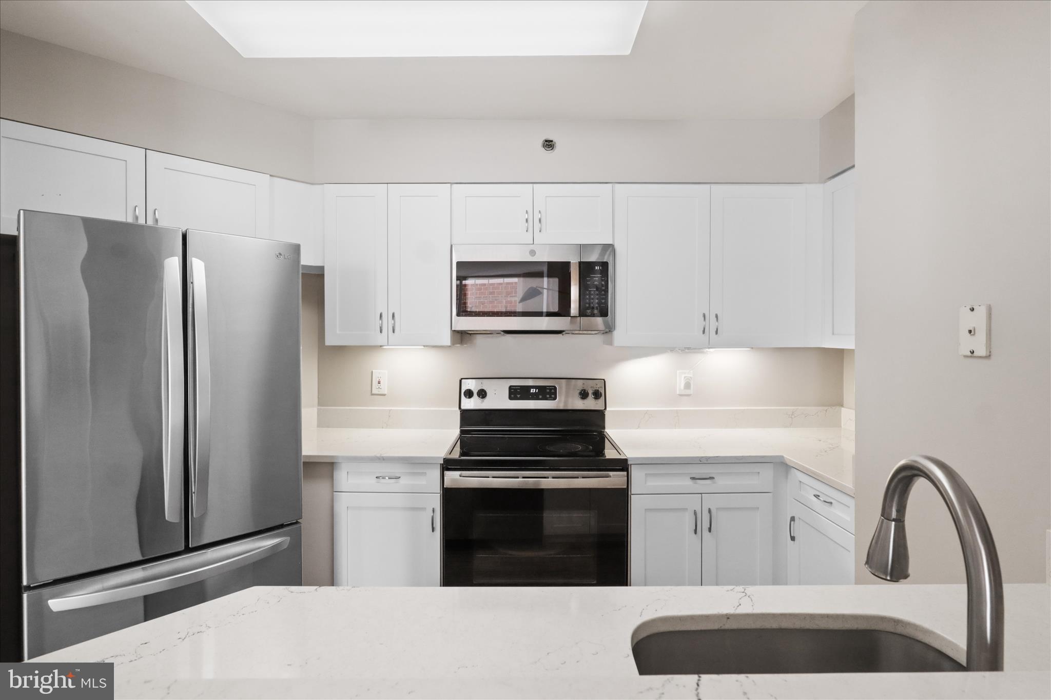 1230 23rd Street Northwest, Unit 918 Washington, DC 20037 - Photo 12 of 30 a kitchen with granite countertop a refrigerator stove and microwave